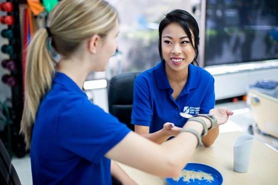 Occupational therapy assistant helping elderly patient regain independence with daily activities